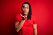 © Krakenimages.com - Young handsome african american afro man with dreadlocks wearing red casual t-shirt looking at the camera blowing a kiss with hand on air being lovely and sexy. Love expression.