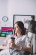 © LIGHTFIELD STUDIOS - Selective focus of computer systems analyst holding paper cup while colleague in office