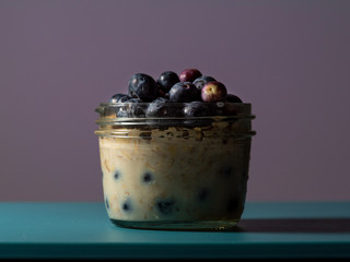 overnight oats in a glass jar plate decorated with blueberries , centered, angle view, selective foc