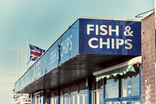 A Vintage Retro Traditional British Seaside Fish And Chips Cafe Sign And Building. English Seaside Fast Food Chip Shop. Lettering And Signs. English Food Restaurant.