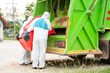 © visoot - Two garbage men in hazmat PPE protective clothing wear medical rubber gloves working together on emptying dustbins for trash removal with truck loading waste and trash bin,Coronavirus Disease 2019.
