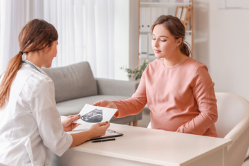 Poster - Young pregnant woman visiting doctor in clinic