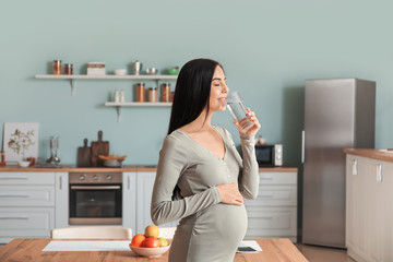 Sticker - Beautiful pregnant woman drinking water in kitchen