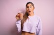 © Krakenimages.com - Young beautiful fitness woman drinking protein chocolate milkshake before gym scared in shock with a surprise face, afraid and excited with fear expression