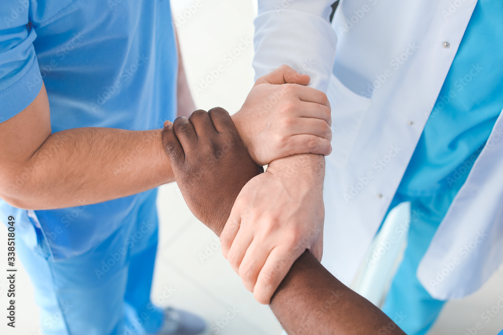 Group of doctors holding hands together in clinic. Unity concept