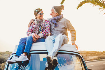 couple of old senior traveler sit down together on the roof of the van enjoy the sunset time togethe