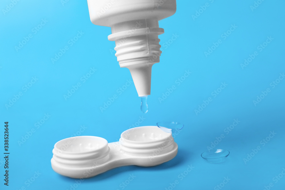 Container for contact lenses and bottle of solution on color background
