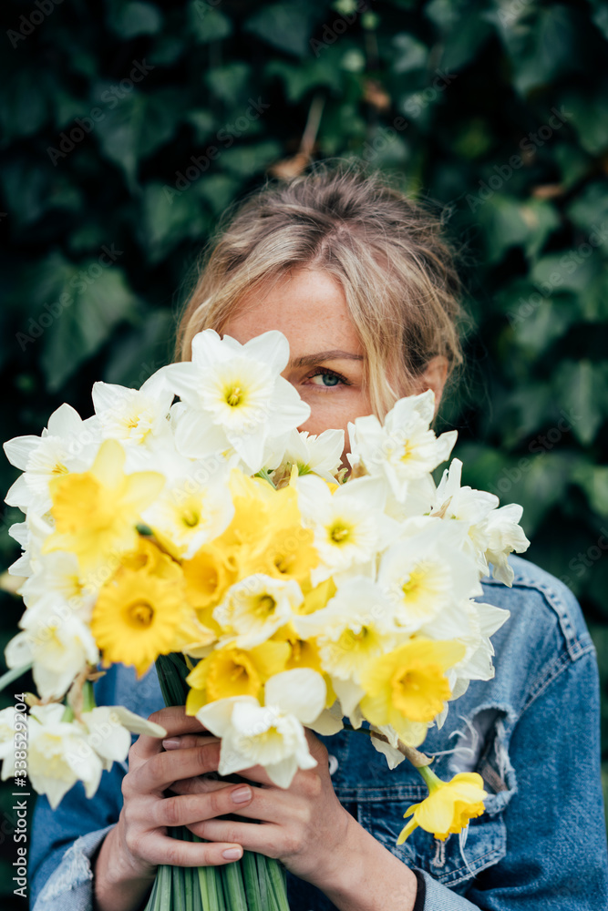 Close portrait of a woman with a bouquet of daffodils. - obrazy, fototapety, plakaty 