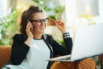 happy trendy housewife with laptop speaking on cell phone