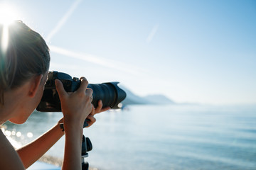 Professional female photographer taking photo of beautiful morning sea