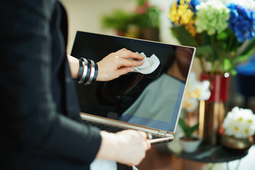 elegant housewife wiping laptop display with cleaning cloth