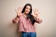 © Krakenimages.com - Young brunette woman wearing casual striped shirt over isolated background showing and pointing up with fingers number ten while smiling confident and happy.
