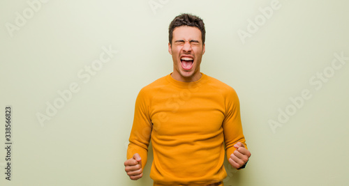Fotomural young arabian man shouting aggressively, looking very angry, frustrated, outrage