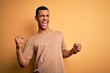 © Krakenimages.com - Young handsome african american man wearing casual t-shirt standing over yellow background Dancing happy and cheerful, smiling moving casual and confident listening to music