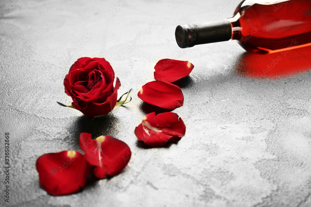 Bottle of wine and rose on grey background