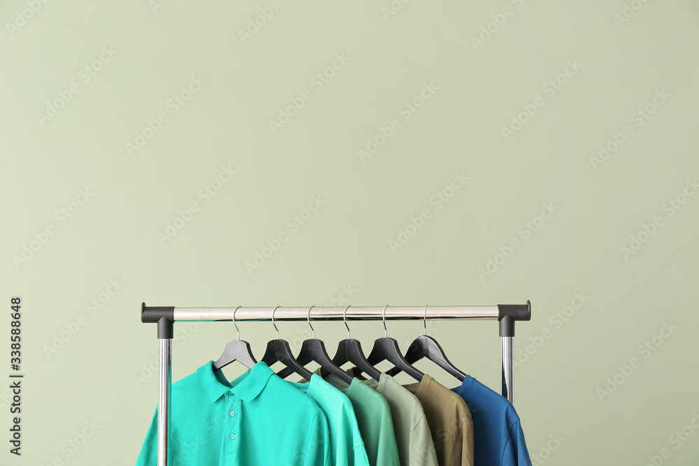 Rack with modern clothes on color background