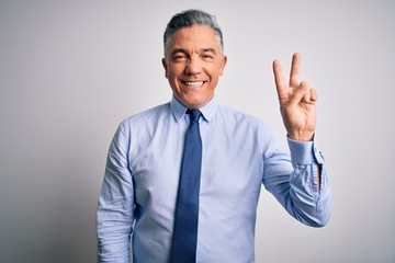 Middle age handsome grey-haired business man wearing elegant shirt and tie showing and pointing up with fingers number two while smiling confident and happy.