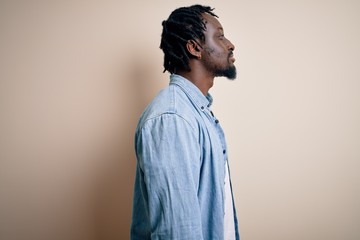 Wall Mural - Young handsome african american man wearing casual denim shirt over white background looking to side, relax profile pose with natural face with confident smile.