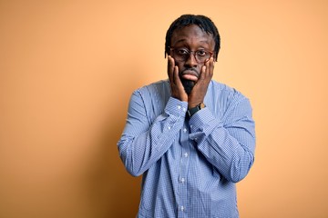 Poster - Young handsome african american man wearing shirt and glasses over yellow background Tired hands covering face, depression and sadness, upset and irritated for problem