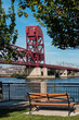 Roosevelt Island Bridge with a wooden bench in the foreground on a sunny day