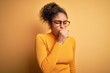 © Krakenimages.com - Young beautiful african american girl wearing sweater and glasses over yellow background feeling unwell and coughing as symptom for cold or bronchitis. Health care concept.