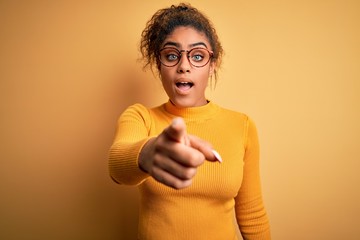 Sticker - Young beautiful african american girl wearing sweater and glasses over yellow background pointing displeased and frustrated to the camera, angry and furious with you