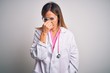 © Krakenimages.com - Middle age beautiful doctor woman wearing pink stethoscope over isolated white background tired rubbing nose and eyes feeling fatigue and headache. Stress and frustration concept.