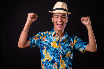 Wall Mural - Portrait of happy young Indian tourist man with hat getting good news