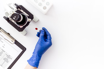 Wall Mural - Bood testing with microscope in laboratory. Sample in hands on white background top view copy space