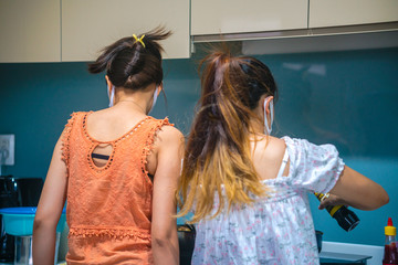 Ho chi minh city, Vietnam - 10 April 2020: people cooking in the kitchen in quarantine for coronavirus wearing protective mask during covid-19 pandemic in Ho Chi Minhcity, Vietnam