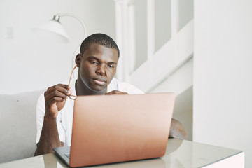 Wall Mural - A man of African appearance in front of a laptop communicating.