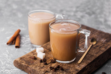 Wall Mural - Cooled coffee with milk, cinnamon sticks, coffee beans, sugar, spoon on the table.