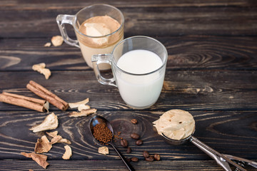 Wall Mural - Delicious and fragrant dalgona coffee in glass cups, cinnamon sticks, dried mushrooms, a spoon of instant coffee, sugar.