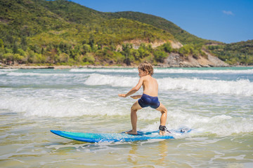 Wall Mural - Healthy young boy learning to surf in the sea or ocean