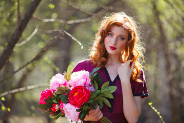 Wall Mural - red-haired girl in a burgundy dress walks in the forest