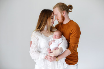 Parenthood, love and family concept - Smiling mother and father holding their baby son.Happy European family, father mother and son baby. Young parents with a newborn son in their arms in the Studio o