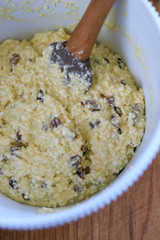 The dough for making Russian traditional home-made cottage cheese pancakes with raisins on a wooden table is kneaded in a bowl