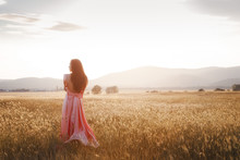 girl dancing in a field in a beautiful pink dress at sunset
