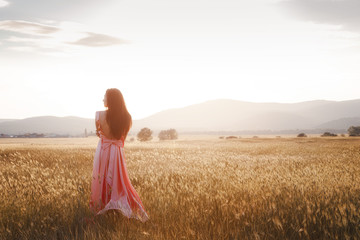 girl dancing in a field in a beautiful pink dress at sunset