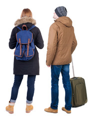 Poster - young couple in winter jacket traveling with suitcas.