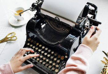 Wall Mural - Aerial view of a woman typing on a retro typewriter blank paper