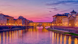 the famous bridge in Florence Ponte vecchio during the blye hour after sunset ,long exposure shot , the lights of the buildings reflect on river arno
