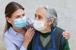 © Ocskay Mark - Caregiver with elderly ill woman wearing mask