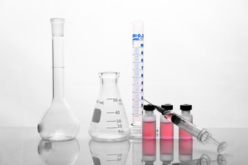 Wall Mural - syringe and red medical drug doses with glass flask cylinder in white science laboratory