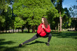© Elena - slim white young woman in leggings and red jacket doing workout in the Park, sports