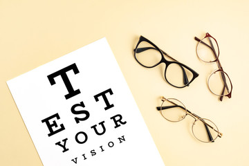 Poster - Collection of eyeglasses with eye test table. Optical store, glasses selection, eye test, vision examination at optician, fashion accessories concept. Top view