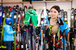 © JackF - Attractive girl choosing ski poles for skiing in store of sports equipment