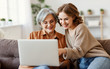 © JenkoAtaman - Young woman with mother using laptop at home
