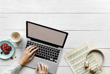 Aerial view of woman using a computer laptop on wooden table music workspace concept