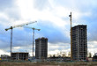 Tower cranes constructing a new residential building at a construction site against blue sky. Renovation program, development, concept of the buildings industry.